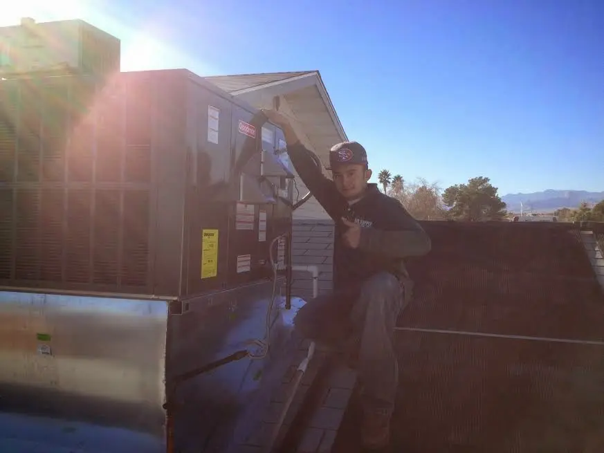 HVAC technician performing Heat Pump Repair on a rooftop unit in Harrisonburg